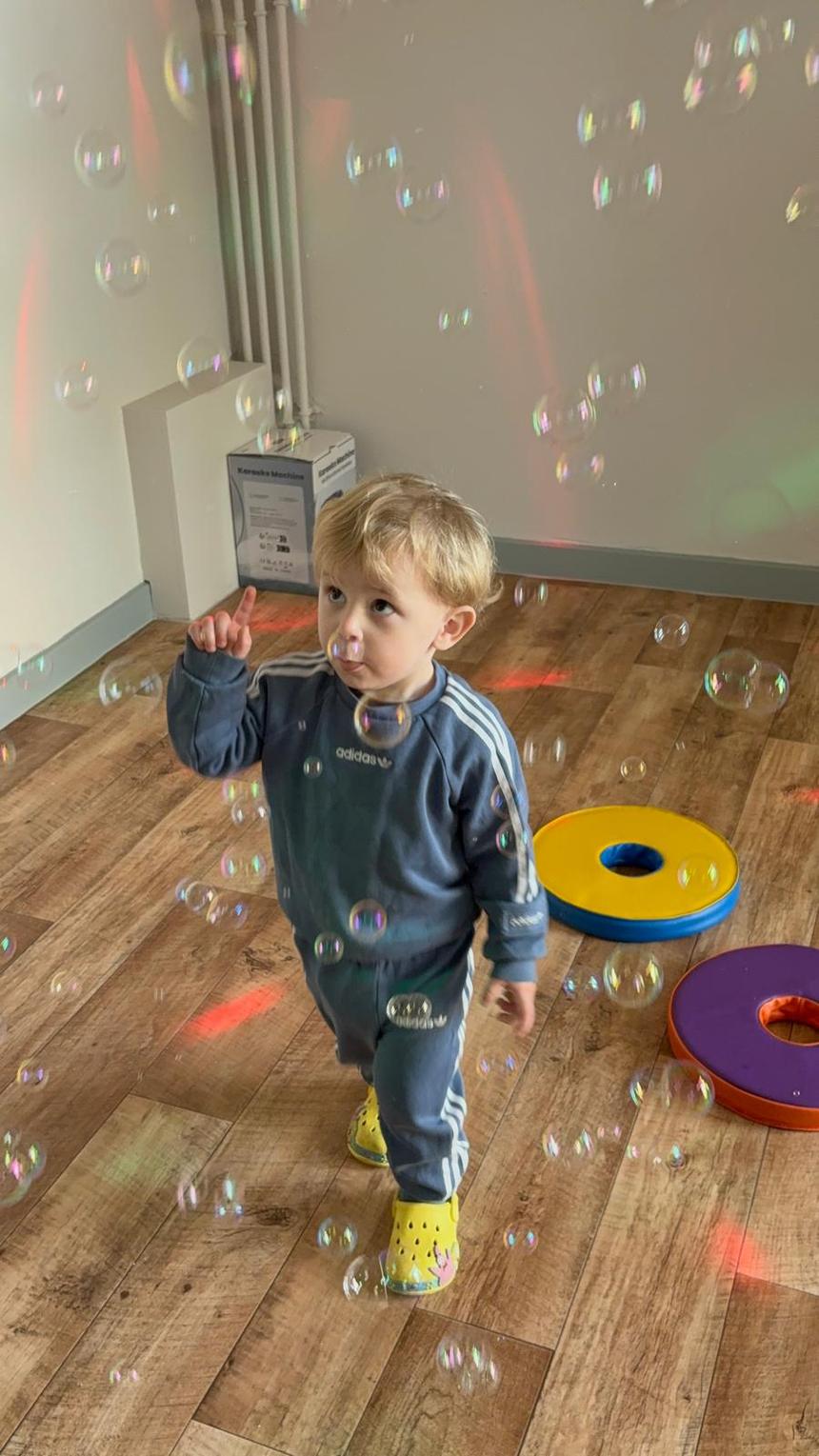A child reaching towards soap bubbles drifting across the studio